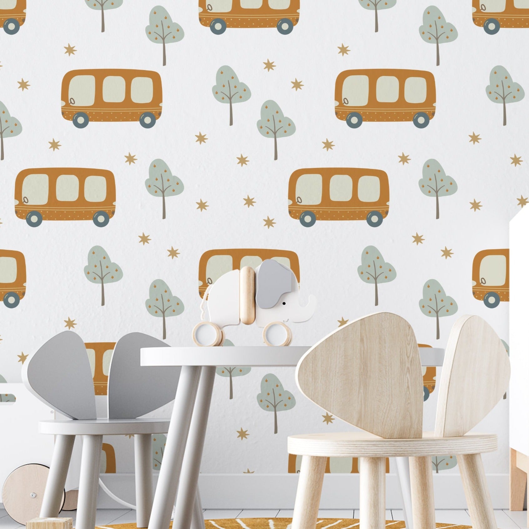 A child's play area adorned with School Bus Wallpaper, depicting orange school buses traveling among whimsical trees and stars, complementing a modern and playful room setting with wooden furniture and a white toy elephant on a table.