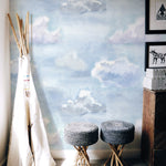  children's corner is transformed into a dreamy space with the "Watercolour Cloud and Skies" wallpaper. A teepee tent, woven stools, and playful decor create an imaginative play area, inspired by the tranquil, cloud-filled sky design of the wallpaper.