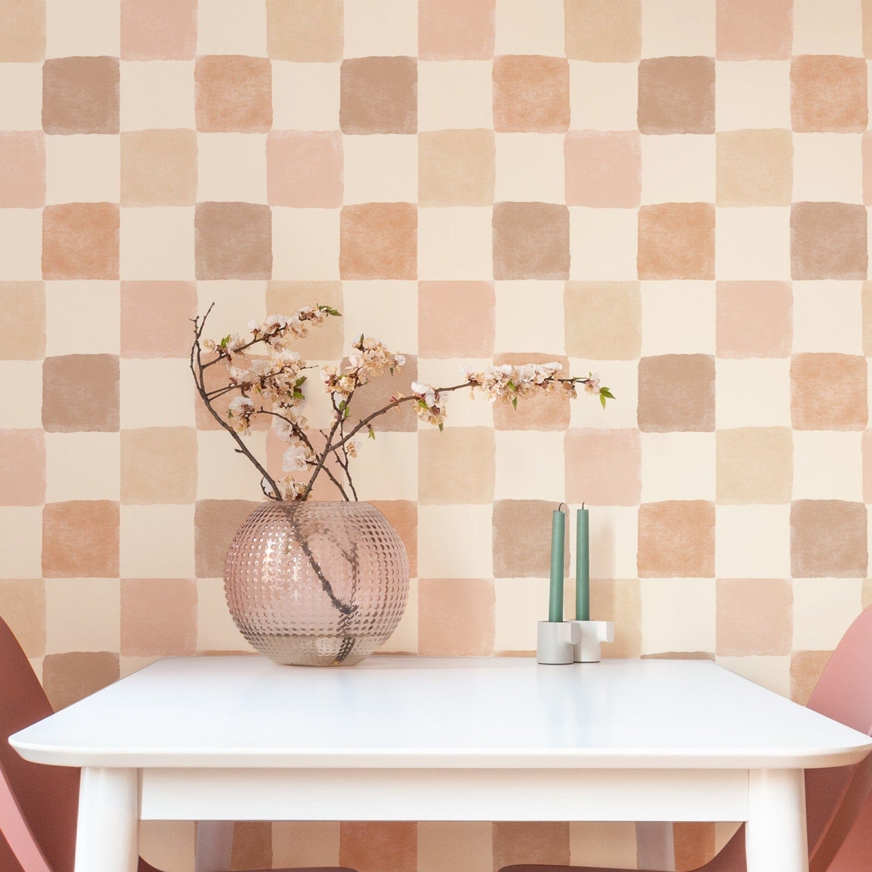 Clémence Wallpaper in a modern dining area, enhancing the space with its soothing checkered pattern of peach, taupe, and beige squares. The wallpaper pairs beautifully with pink dining chairs and a simple white table, creating a chic and cozy ambiancev