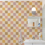 Cécile Wallpaper II displayed in a contemporary bathroom setting, showing a checkered design in muted pastels that enhances the space with a modern and elegant touch, complemented by minimalistic decor and a white bathroom suite.