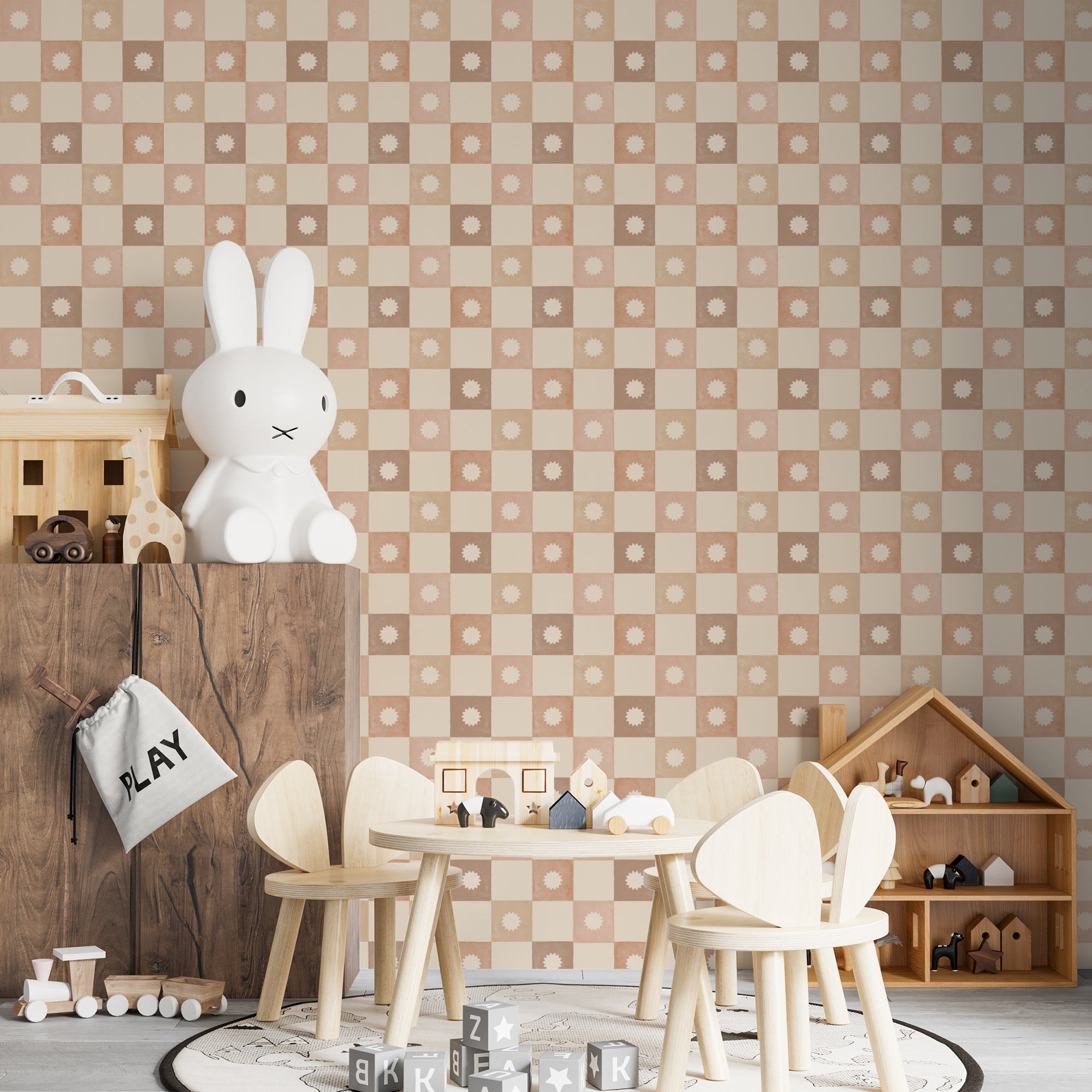 A children’s playroom wall covered with Marie Wallpaper, showcasing a pastel checkered pattern with white starburst designs in each square. The room is decorated with a wooden toy storage unit and minimalist children's furniture, enhancing the playful and creative environment