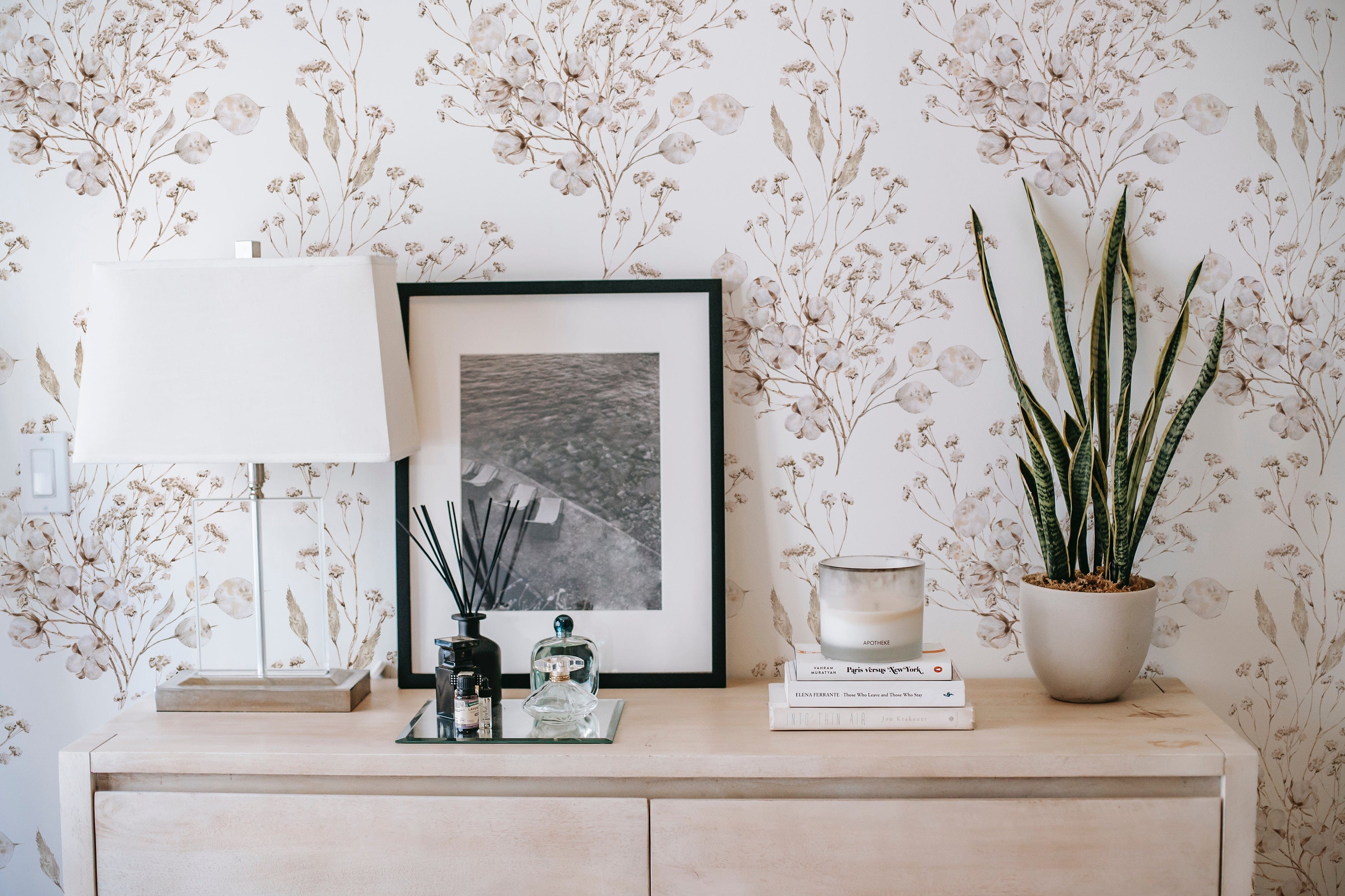 A modern dresser against the Boho Winter Floral Wallpaper, with the botanical print providing a stylish backdrop to the simple and elegant home decor items.