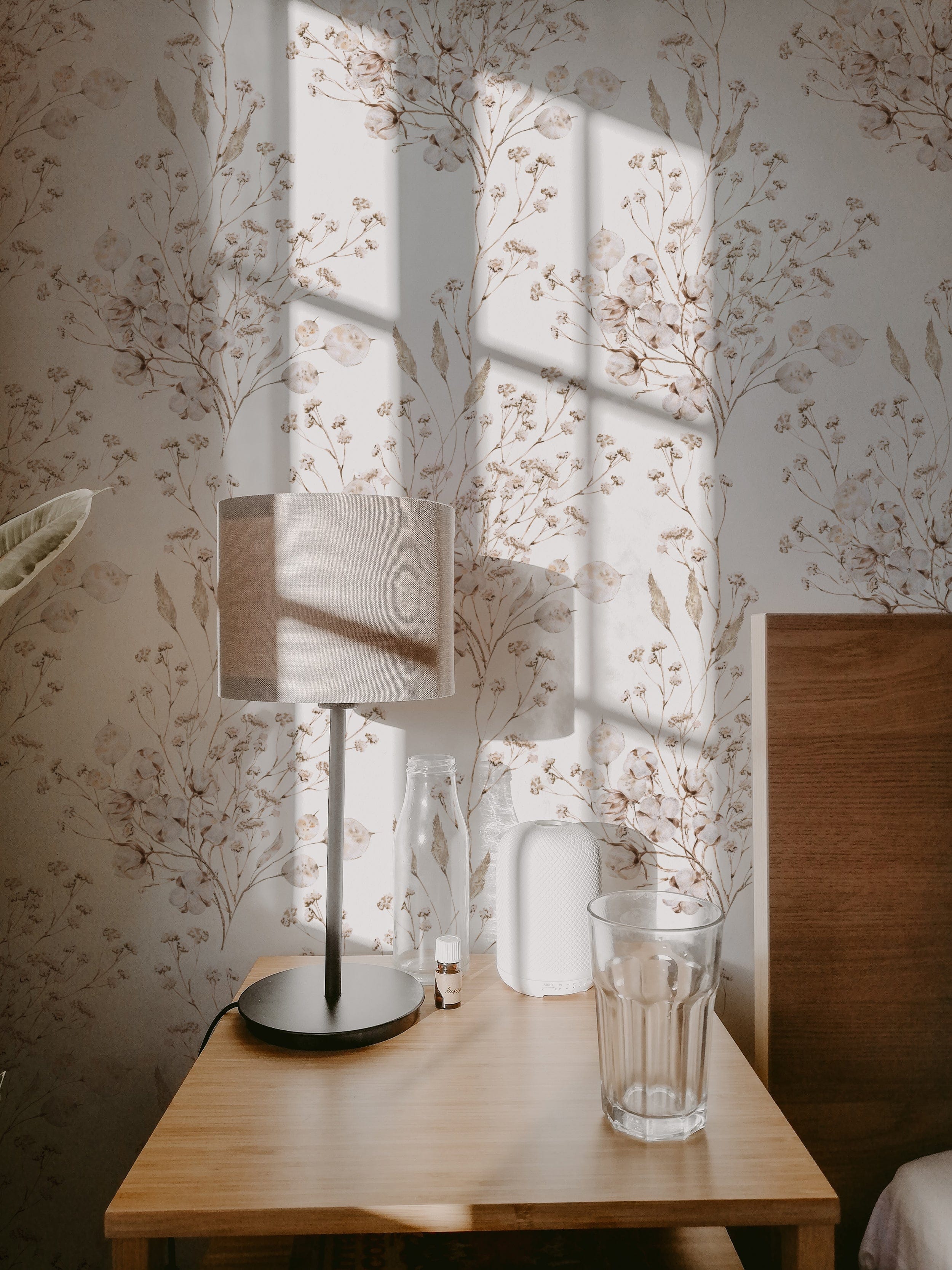 A cozy corner illuminated by sunlight filtering through sheer curtains showcases the Boho Winter Floral Wallpaper, complementing the warm and inviting reading space.
