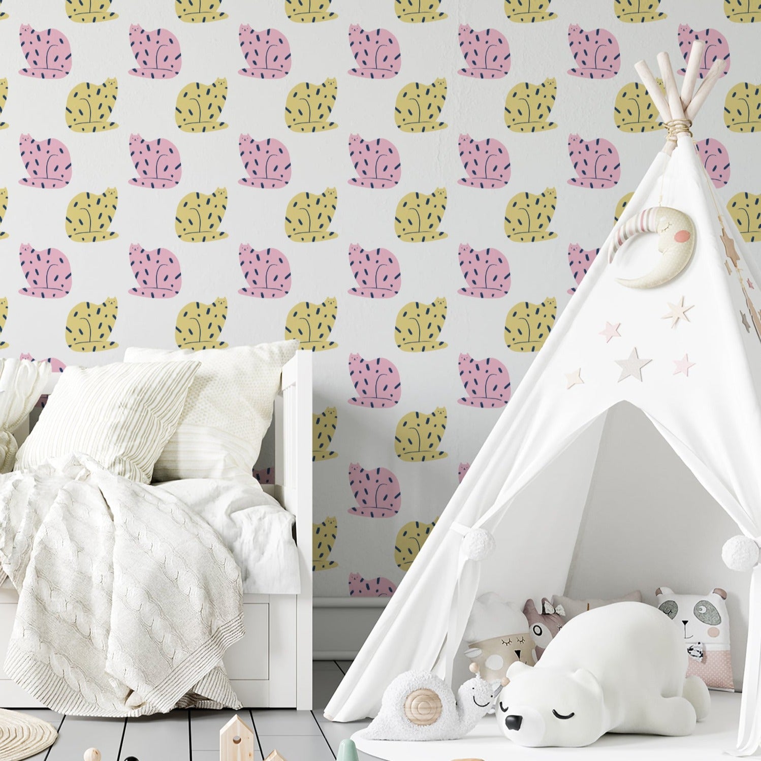 Room setup with a wall covered in cat-themed wallpaper displaying a sequence of pink and yellow cats with black accents. The room features a white teepee with star details and a plush polar bear, creating a cozy and imaginative children's play area