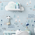 A children's playroom adorned with the "Nordic Adventure Wallpaper," which provides a backdrop of abstract trees and mountains in shades of blue, white, and orange. The room is equipped with modern children's furniture including a white elephant rocker, a cloud-shaped shelf, and playful decorations that complement the adventurous theme of the wallpaper.