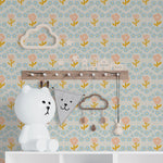 A cheerful and playful nursery room decorated with Baby Spring Wallpaper, featuring a pattern of soft pink flowers and delicate blue floral accents. The room includes children’s decor such as a whimsical cloud shelf and playful animal figurines, creating an enchanting and inviting space for little ones.