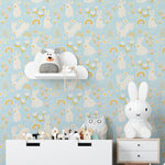 A nursery room showcasing a wall covered in light blue wallpaper featuring white rabbits and small rainbows, accompanied by child-friendly decor like toy shelves and plush animals