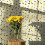 Yellow Spring Wallpaper adorned with watercolor yellow flowers and green leaves, highlighted by a vase of yellow flowers on a wooden table.