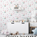 A modern nursery room showcasing the 'Fairy and Flowers III' wallpaper adorned with pink and teal butterflies and small floral accents. The room features contemporary white furniture and children’s toys, complementing the delicate and whimsical nature of the wallpaper.