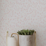 Minimalist style room showcasing the Subtle Botanica Wallpaper III with delicate pink foliage patterns, complemented by a sleek white clock and a potted succulent on a floating shelf