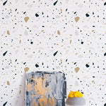 Stone Terrazzo Wallpaper in a stylish interior, complementing a modern painting and a textured vase with vibrant yellow flowers, highlighting the wallpaper's versatility and contemporary appeal.