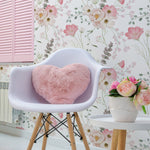Flourish Wallpaper in a cozy living space featuring a white chair with wooden legs, a pink heart-shaped cushion, a side table with a vase of pink flowers, and a soft floral wallpaper with delicate pink and white flowers and green foliage