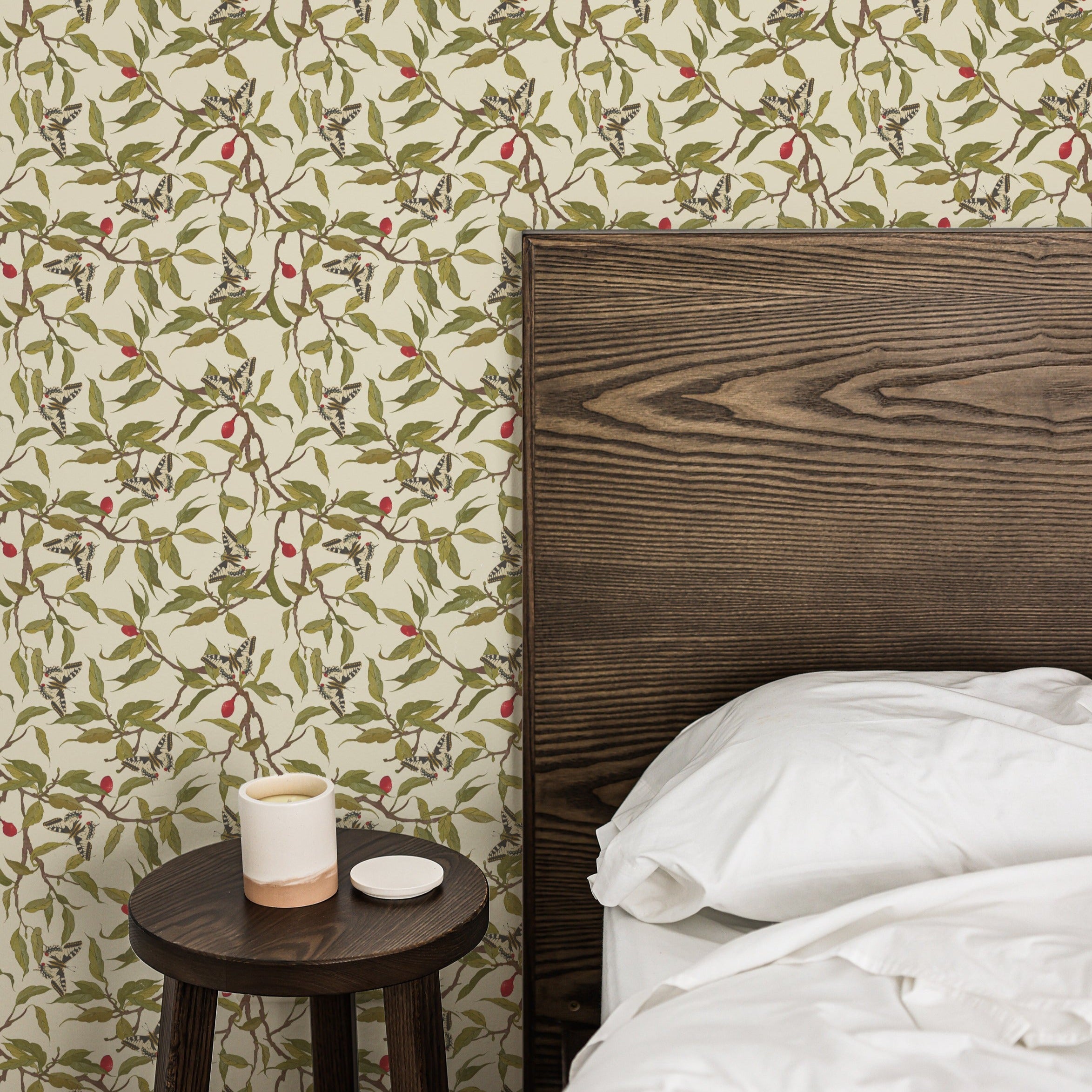 A stylish bedroom with a wooden headboard and a minimalist side table, set against a wall adorned with Vintage Garden Wallpaper. The wallpaper's nature-inspired pattern enhances the room's aesthetic, adding a touch of elegance and tranquility.