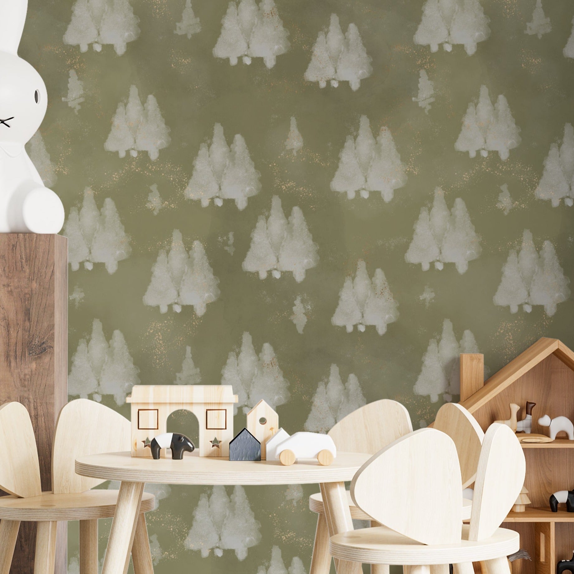 A children’s play area adorned with Shimmer Tree Wallpaper, featuring gentle white trees on an olive green background with subtle gold flecks. The scene is set for creative play with wooden toys and comfortable seating, making it a perfect backdrop for a nursery or playroom