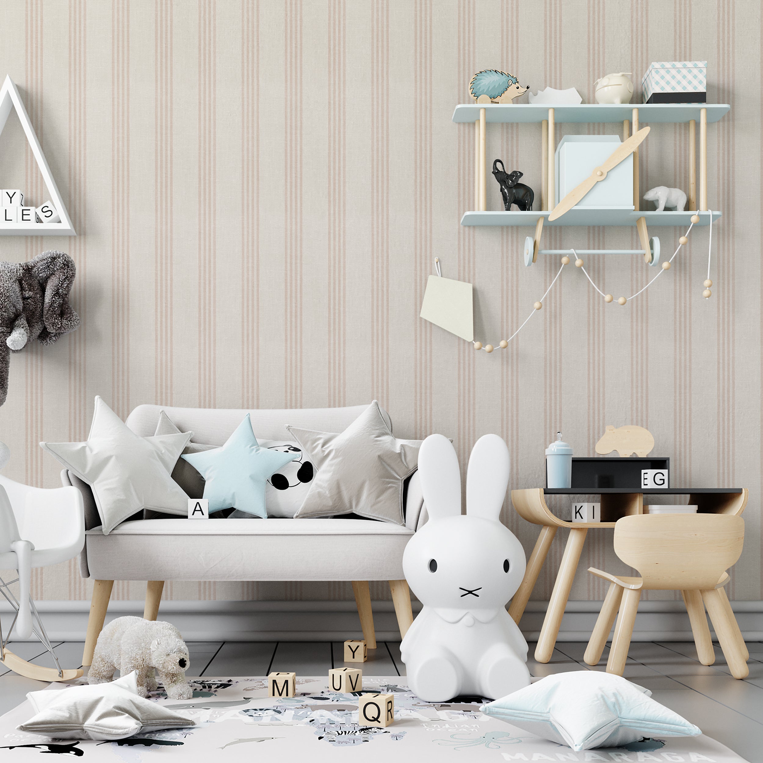 A playful and whimsical children's room with a beige-striped "Ticking Fabrics 8" wallpaper providing a warm backdrop. The room features a variety of child-friendly decorations, including a plush bunny chair, a sofa adorned with star-shaped pillows, and wooden toys scattered on the floor, creating an inviting and imaginative play space.