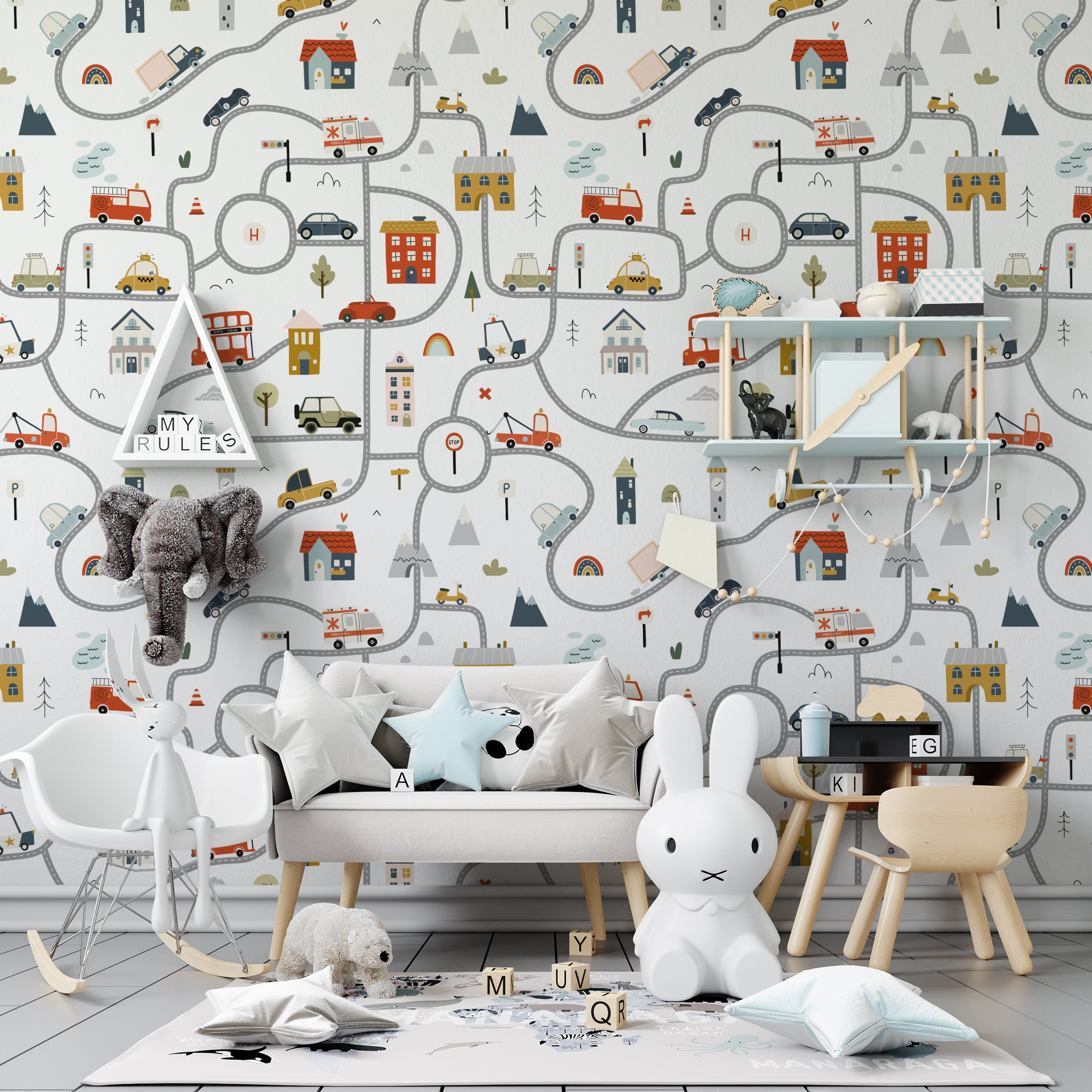 A child's bedroom wall covered with Busy Town Wallpaper, depicting a bustling town scene with whimsical roads, assorted vehicles, and charming buildings. The detailed and colorful design creates an engaging environment, complemented by children’s furniture and toys
