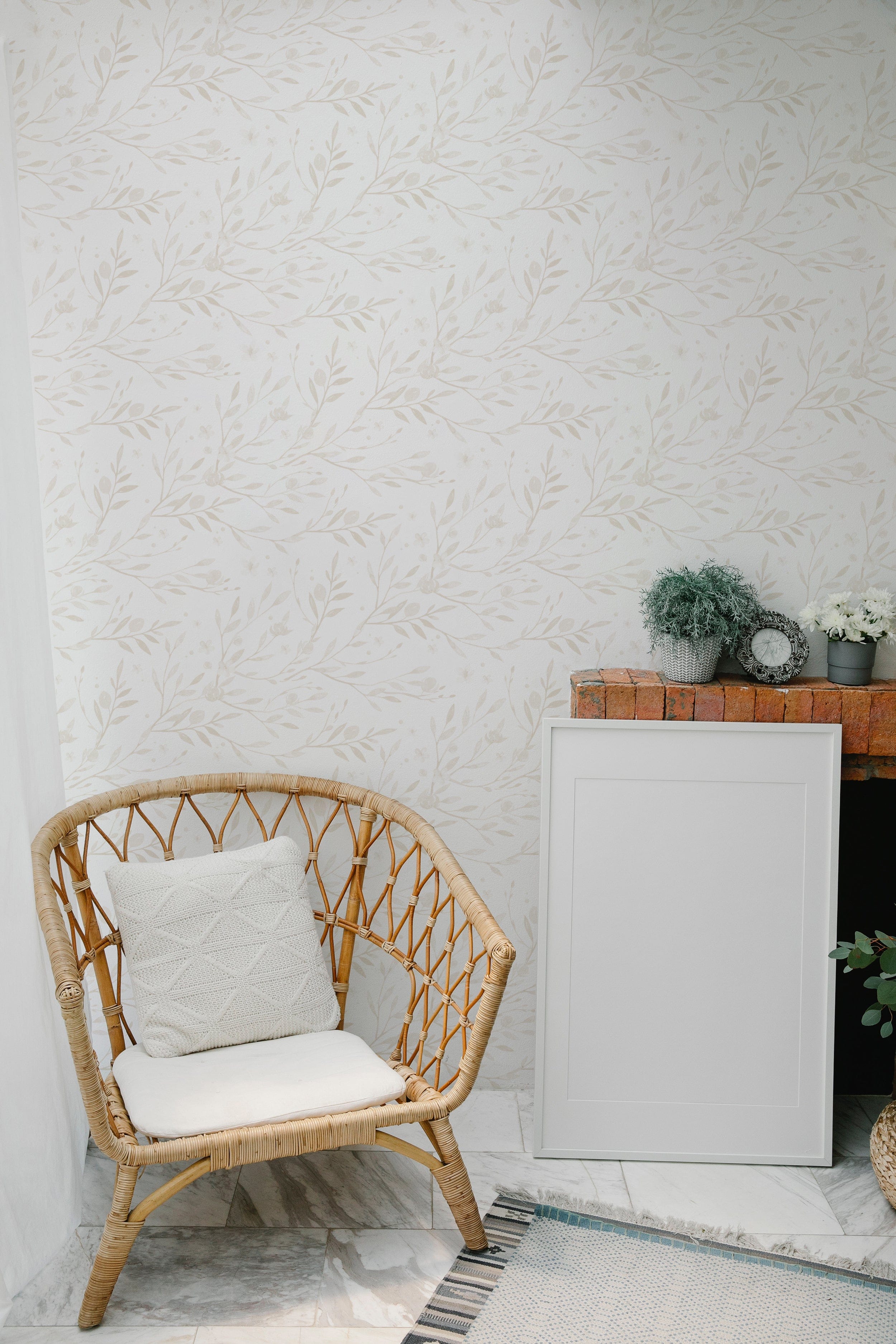 A cozy room corner featuring the Watercolour Spring Bird Wallpaper in Ecru with a natural wicker chair, creating a serene and inviting space with its delicate branch and bird design.