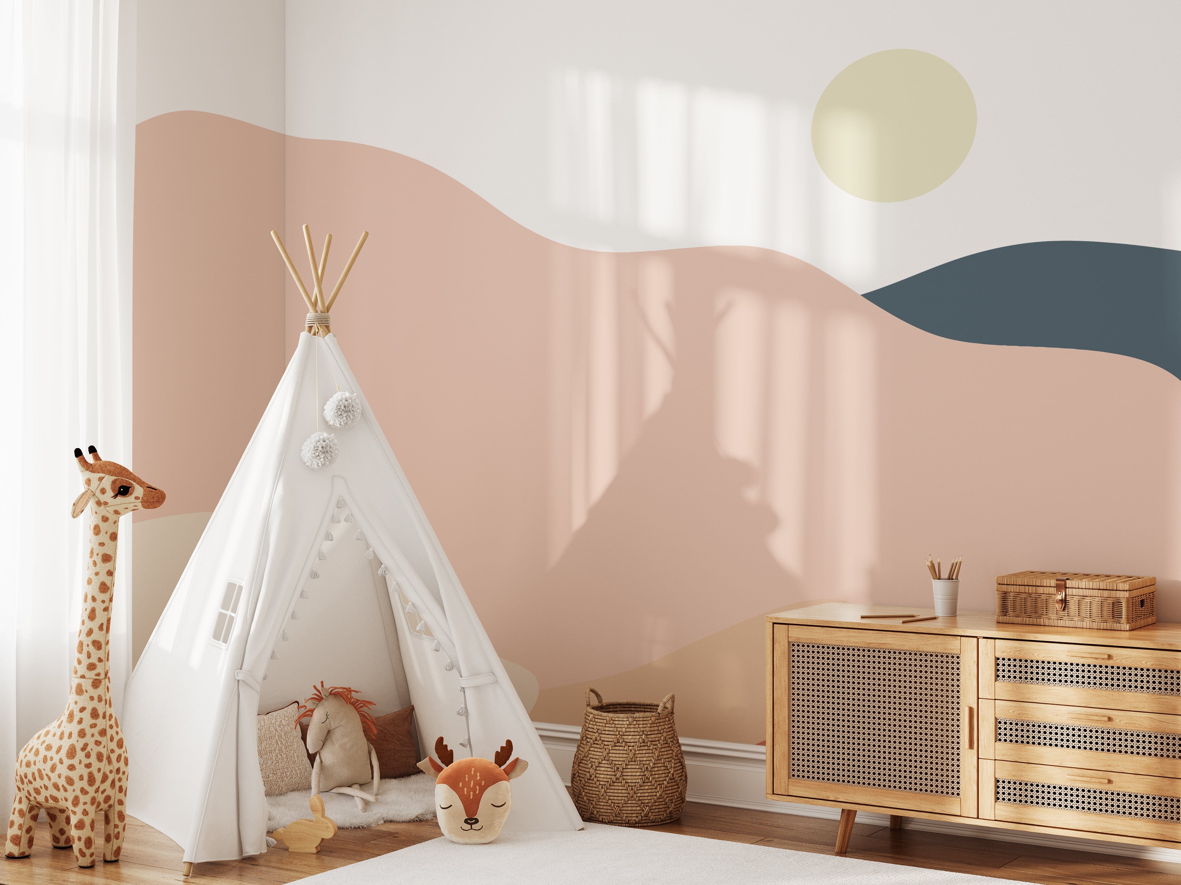 Pastel Playground Kids Mural Wallpaper in a charming children's room with a white teepee, plush giraffe toy, wicker basket, and a wooden dresser. The wallpaper features soft, wavy pastel colors with a sun motif