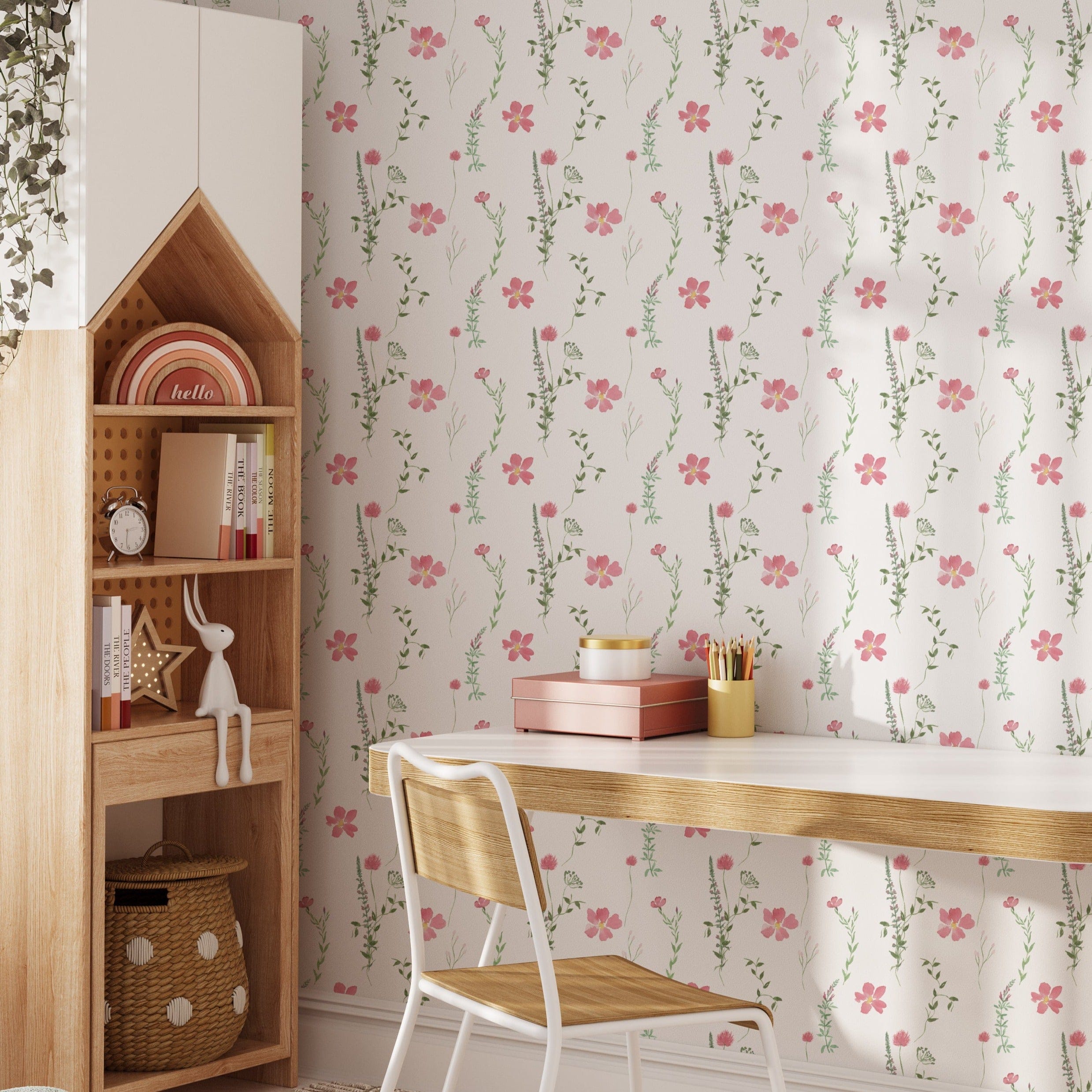 A cozy study area featuring the Spring Serenity Wallpaper, highlighting its pink flower and green leaf pattern, with a white desk and wooden bookshelf filled with books and decor items