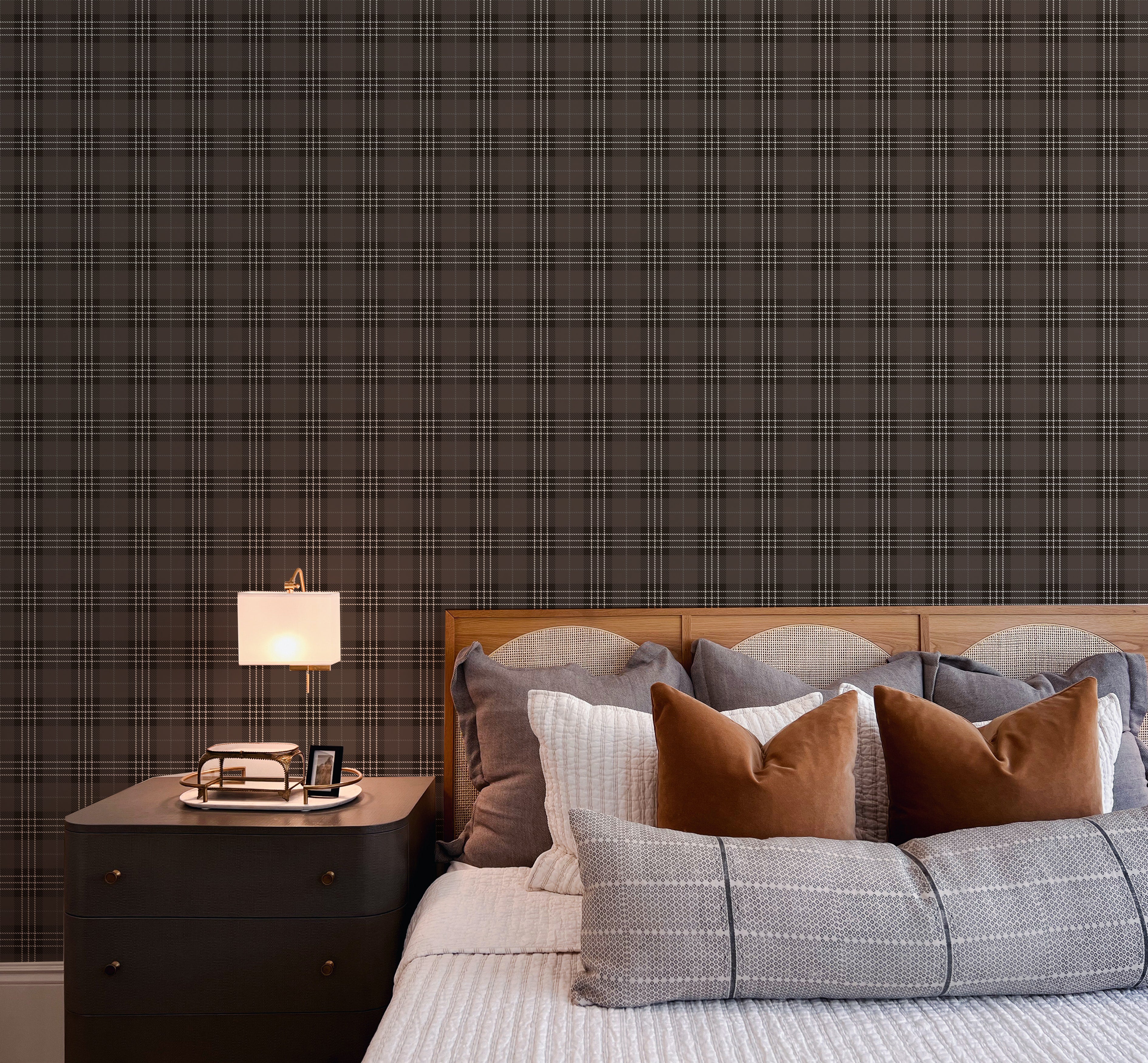 A luxurious bedroom accentuated by Dark Plaid Wallpaper - Black, providing a rich, textured backdrop to a bed with assorted pillows. The pattern adds depth and a traditional touch to the modern room, complemented by a sleek bedside table and a contemporary lamp.