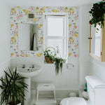 A bathroom decorated with 'Spring Animal Watercolour Wallpaper' showcasing cheerful yellow chicks and floral designs, complementing a white interior with natural greenery.