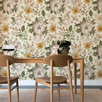 A dining area with natural wood furniture against a wall covered in Floral Wallpaper - Sunny, which displays a vibrant array of hand-drawn flowers in yellows and greens on a cream background, creating a fresh and inviting botanical theme.