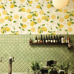 Lemon Floral Wallpaper featuring a lively design of yellow lemons and green leaves, adorning a kitchen wall with a green tiled backsplash and a shelf with bottles and plants.