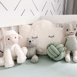 A charming nursery scene with a white crib against a wall decorated with 'Minimal Line Wallpaper', featuring an array of diagonal black lines on a white background. Plush toys and a cushion adorn the crib.