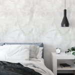 Modern minimalist bedroom featuring Grey Limewash Wallpaper that offers a subtle, textured backdrop to a cozy bed with crisp white linens and a sleek bedside setup