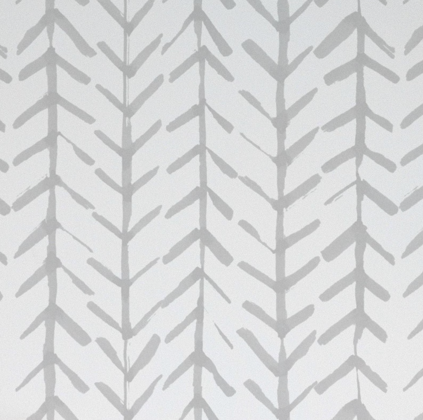 A detailed view of the Hand Painted Chevron Arrow Wallpaper showcasing a repetitive pattern of hand-painted gray chevron arrows on a white background, evoking a sense of rustic charm and artisanal craftsmanship
