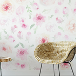 A stylish home office space with a wall adorned with 'Pink Watercolour Floral Wallpaper', featuring a dreamy array of blush and rose pink watercolor flowers, creating a romantic and inspiring backdrop for the natural wicker chair and wooden desk.