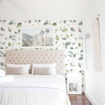 A serene bedroom setting showcasing the Sunny Watercolour Floral wallpaper, featuring delicate green and beige watercolour leaves on a white background, accentuating the tranquil and airy ambiance of the room