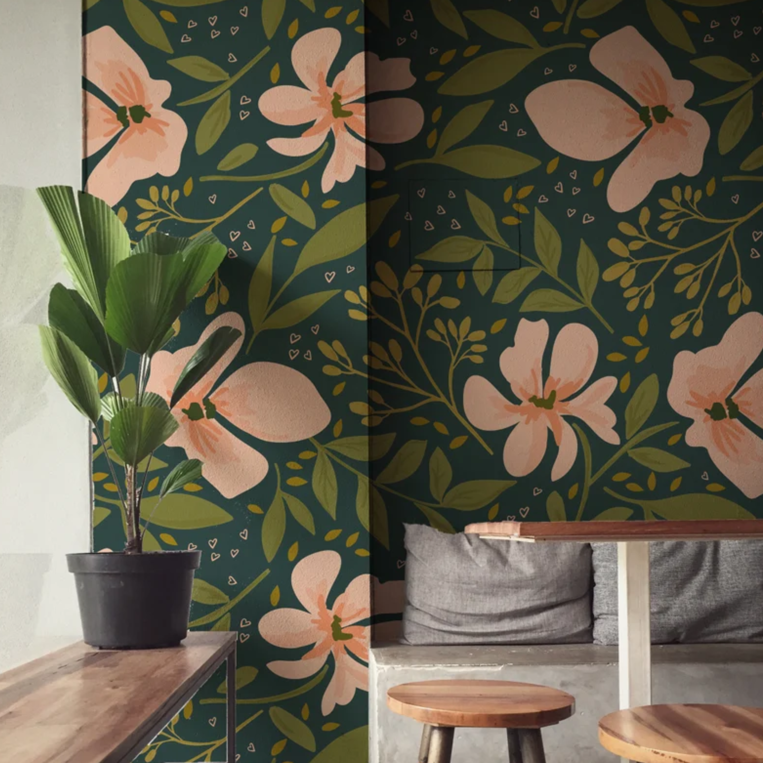 A chic dining area with 'Floral Love Watercolour Wallpaper' providing a captivating dark backdrop adorned with large watercolor pink blossoms and leaves, complemented by natural wood furniture and lush green plants