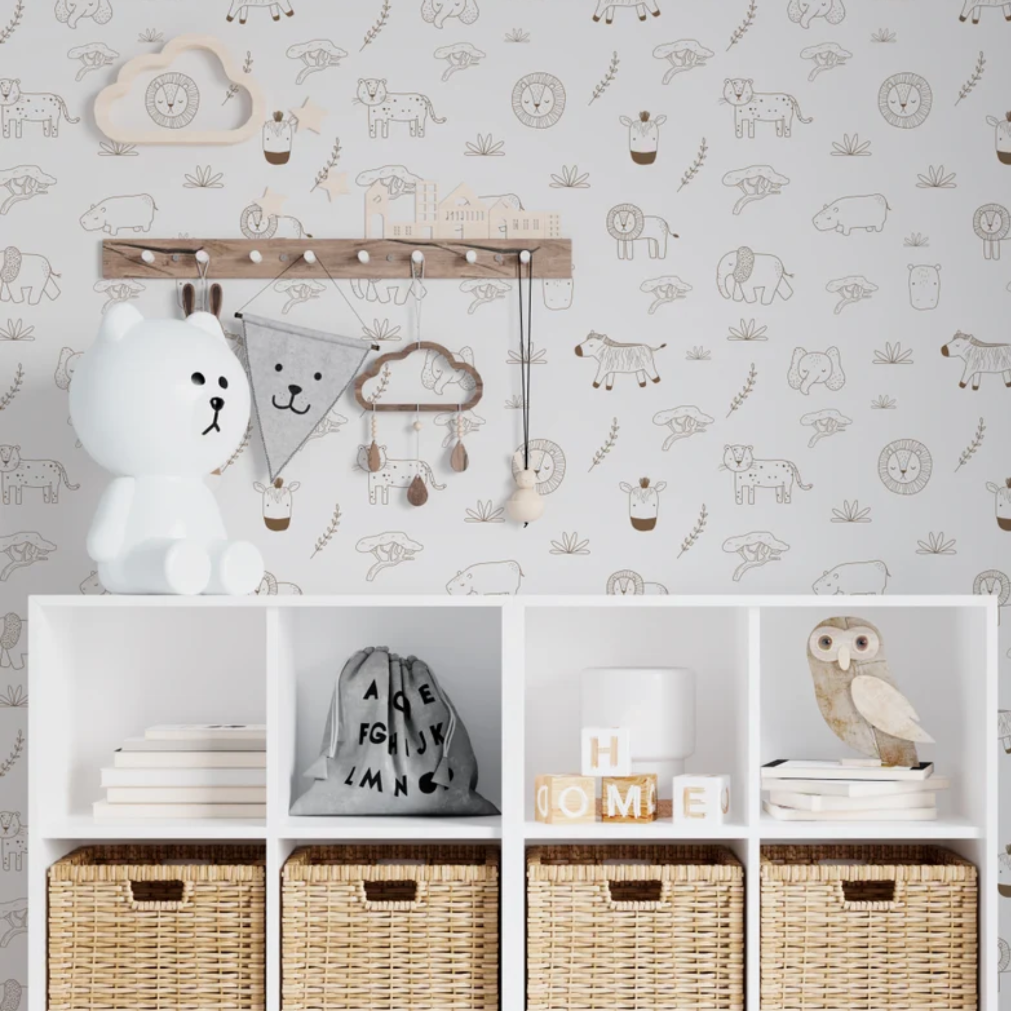 A cozy nursery corner showcasing Safari Jungle Wallpaper with a cute array of hand-drawn-style safari animals on a soft beige background. The scene includes a white storage unit with wicker baskets, a playful bear lamp, children’s accessories, and a wooden coat rack adorned with a charming cloud-shaped clock and baby essentials.