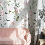 A cozy corner of a room illuminated by natural light showcases the 'Watercolour Hummingbird Floral Wallpaper', with delicate pink flowers and fluttering hummingbirds creating a serene and picturesque scene