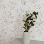 Elegant white vase with fresh flowers set against the Dainty Floral Line Wallpaper, emphasizing the detailed floral line art