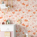 Charming nursery setup showcasing 'Floral Love Wallpaper' with patterns of large coral and pink tulip-like flowers, paired with children's toys and decor items on a white furniture unit.