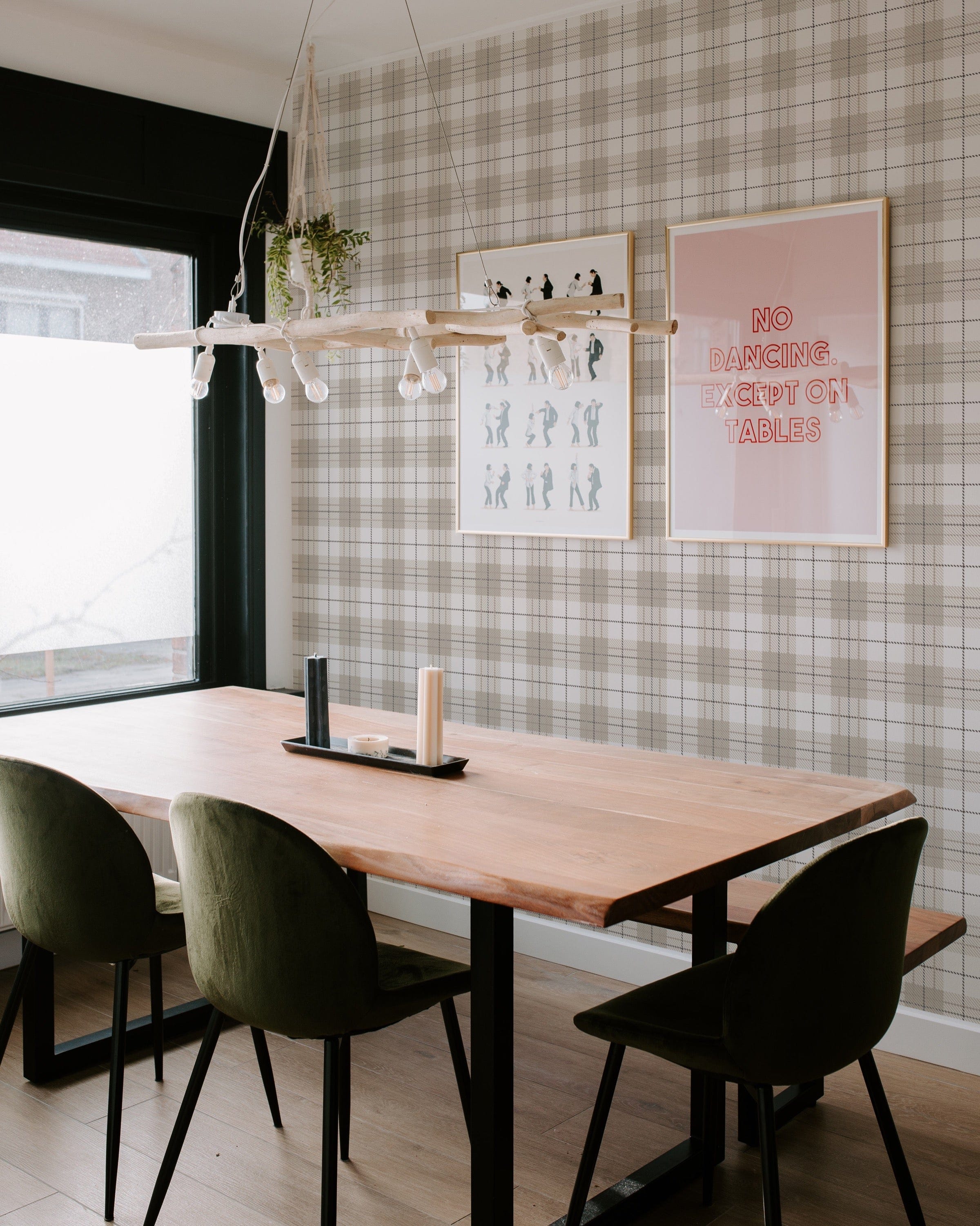 A contemporary dining area accented with Winter Plaid Wallpaper, featuring a solid wood table with velvety green chairs. The wallpaper's plaid pattern provides a timeless backdrop, harmoniously blending with the modern furnishings and light-hearted wall art.
