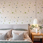 A cozy bedroom with 'Ikebana Floral Wallpaper' enhancing the wall behind a bed with plush green and gray pillows, with the natural floral pattern contributing to a restful ambiance.