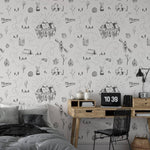 The Big Adventure Kids Wallpaper is featured in a cozy bedroom setup with a modern wooden desk and stylish decor, infusing the space with a sense of adventure through its charming and intricate line drawings of wilderness scenes.