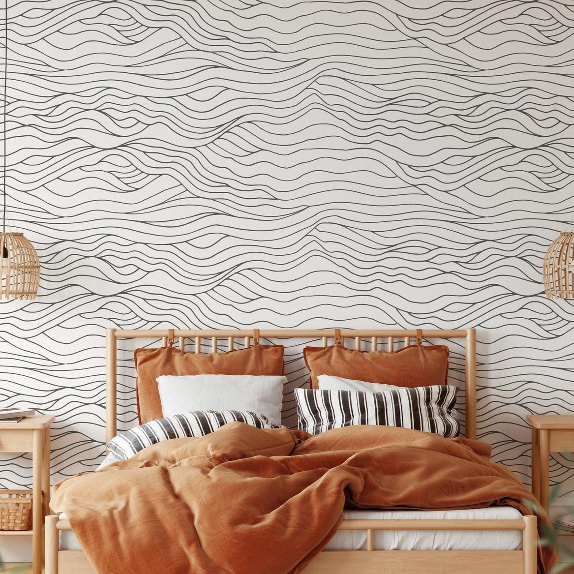 A stylish bedroom with a wooden bed frame and rust-colored bedding. The background features Modern Line Abstract Wave Wallpaper, with fluid, black wavy lines on a white background, creating a serene and contemporary ambiance.