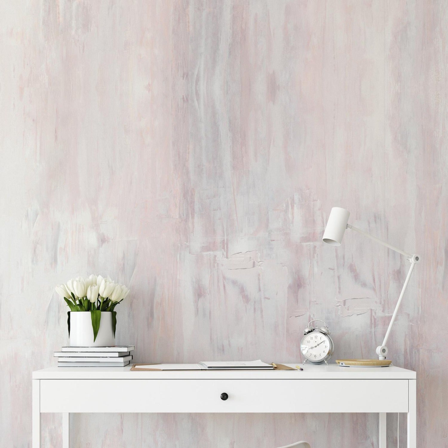A minimalist workspace with a desk against a wall covered in pink Paint Texture Wallpaper IV, showcasing soft, uneven brushstrokes that add depth and a handcrafted feel to the room.