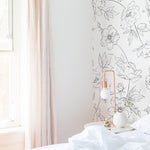 Bright bedroom with Dainty Floral Line Wallpaper - Extra Large featuring a black and white floral line art design on a light background, creating a fresh and elegant atmosphere with a wooden bed and minimalist decor.
