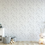 A child's playroom with walls covered in Nursery Watercolour Floral - Fog wallpaper, a subtle and soft gray botanical pattern, complemented by playful décor including a large bunny lamp and a white storage unit filled with toys.