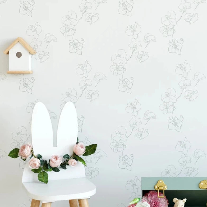 A child’s nursery room wall covered with Floral Line Art Wallpaper, showcasing minimalist sketched flowers, complemented by a white chair with bunny ears and a floral wreath