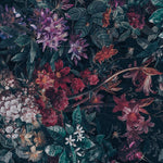 An intricate Dark Luxury Floral Wallpaper - Large adorns a wall with lush, overscaled flowers in deep blues and purples, accented with touches of pink and red, against a dark background, giving a dramatic and opulent touch to the interior space.