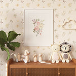 A charming corner of a child's room featuring Sunny Floral Wallpaper with pastel flowers, accessorized with wooden toys and whimsical stuffed animals on a rattan cabinet.
