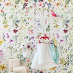 A playful and inviting corner of a room showcasing Hera's Floral Wallpaper, with its cheerful floral pattern that brightens the area, complemented by a charming white dress hung on a rack, creating a fairy-tale atmosphere.
