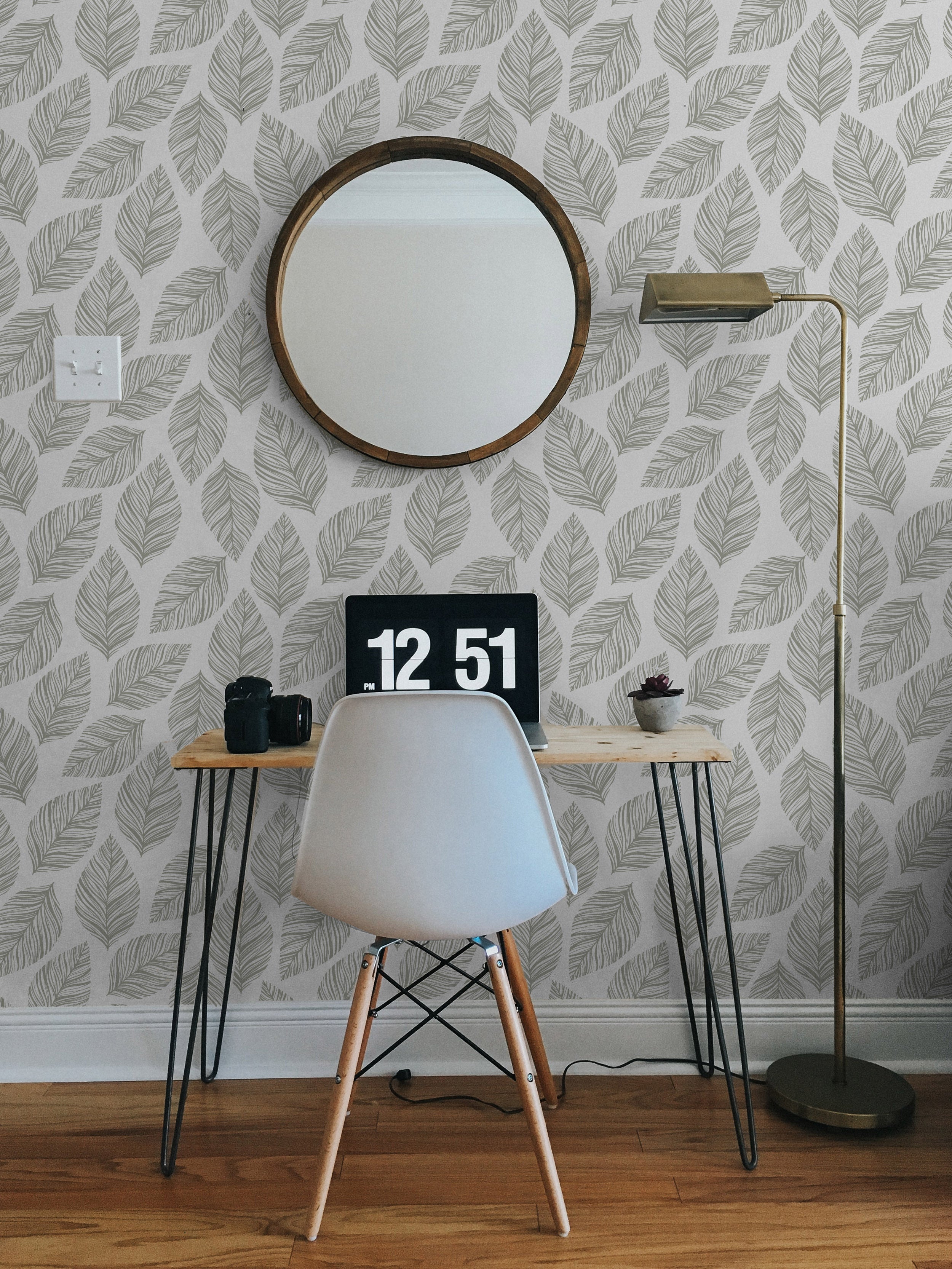 A modern home office setup with a minimalistic desk and chair against a wall adorned with Leafy Wallpaper, featuring an elegant pattern of grey leaf outlines on a white background, enhancing the space with a fresh, botanical vibe.