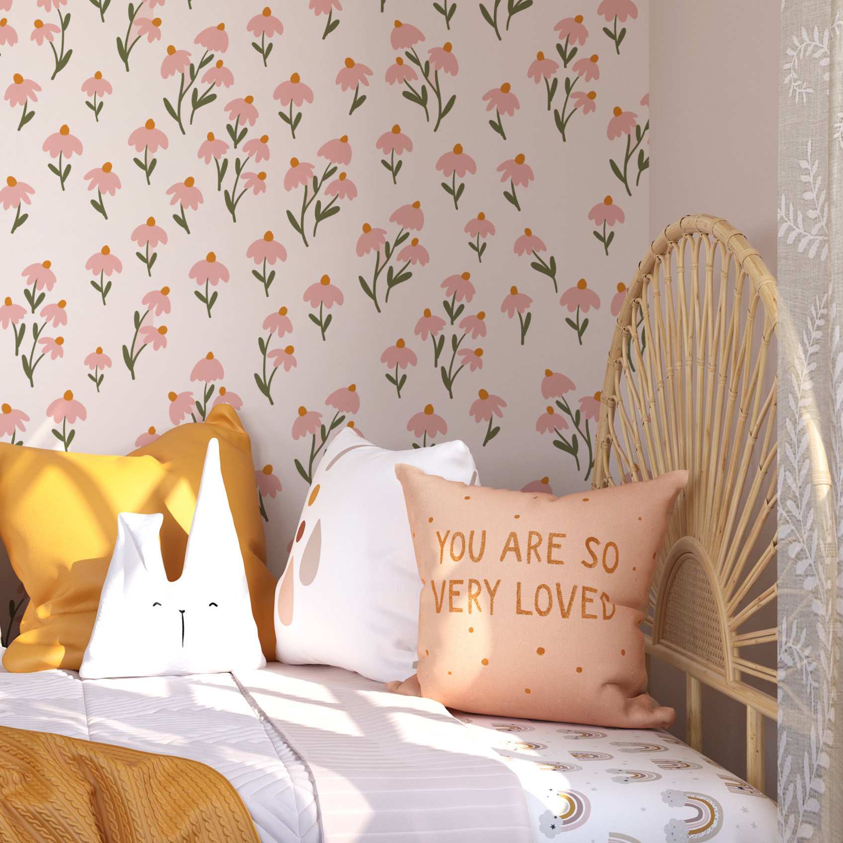 A child's room featuring the Floral Love Wallpaper- Pink on the wall, creating a heartwarming and inviting atmosphere. The wall is adorned with playful pillows, including one with the affectionate phrase "You are so very loved," alongside a cozy yellow blanket and a rattan peacock chair.